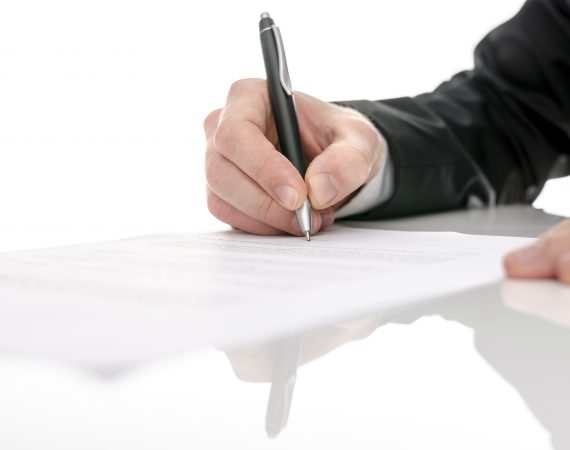 Business man signing a contract on a white table. With selective focus.
